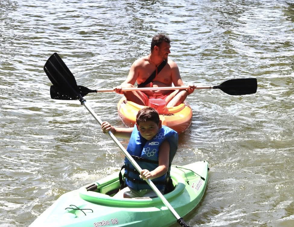 A man and a boy kayaking in a lake.